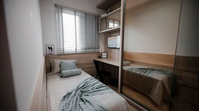 A cozy and minimalist bedroom interior featuring a single bed and a small workspace.