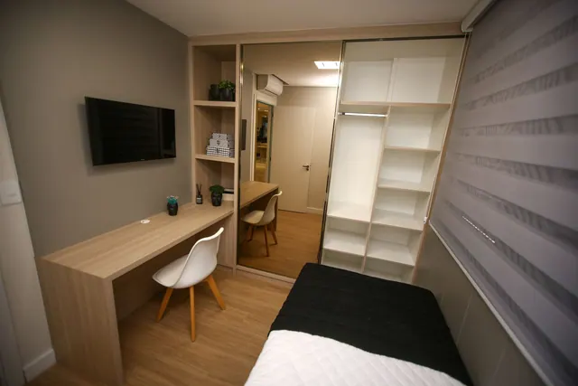 Elegant minimalist bedroom featuring a desk, mirror, and shelving unit in a stylish interior.