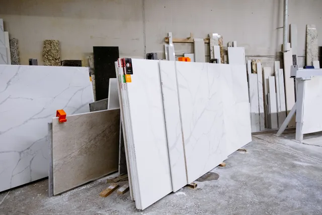 Wide view of granite and marble slabs neatly arranged in a factory setting, showcasing variety and texture. Materials for small space living, compared across Phoenix heat and Miami humidity