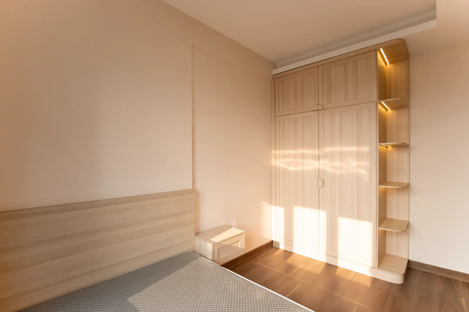 Cozy empty bedroom featuring wooden furniture and warm lighting.