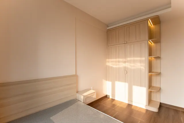 Cozy empty bedroom featuring wooden furniture and warm lighting.